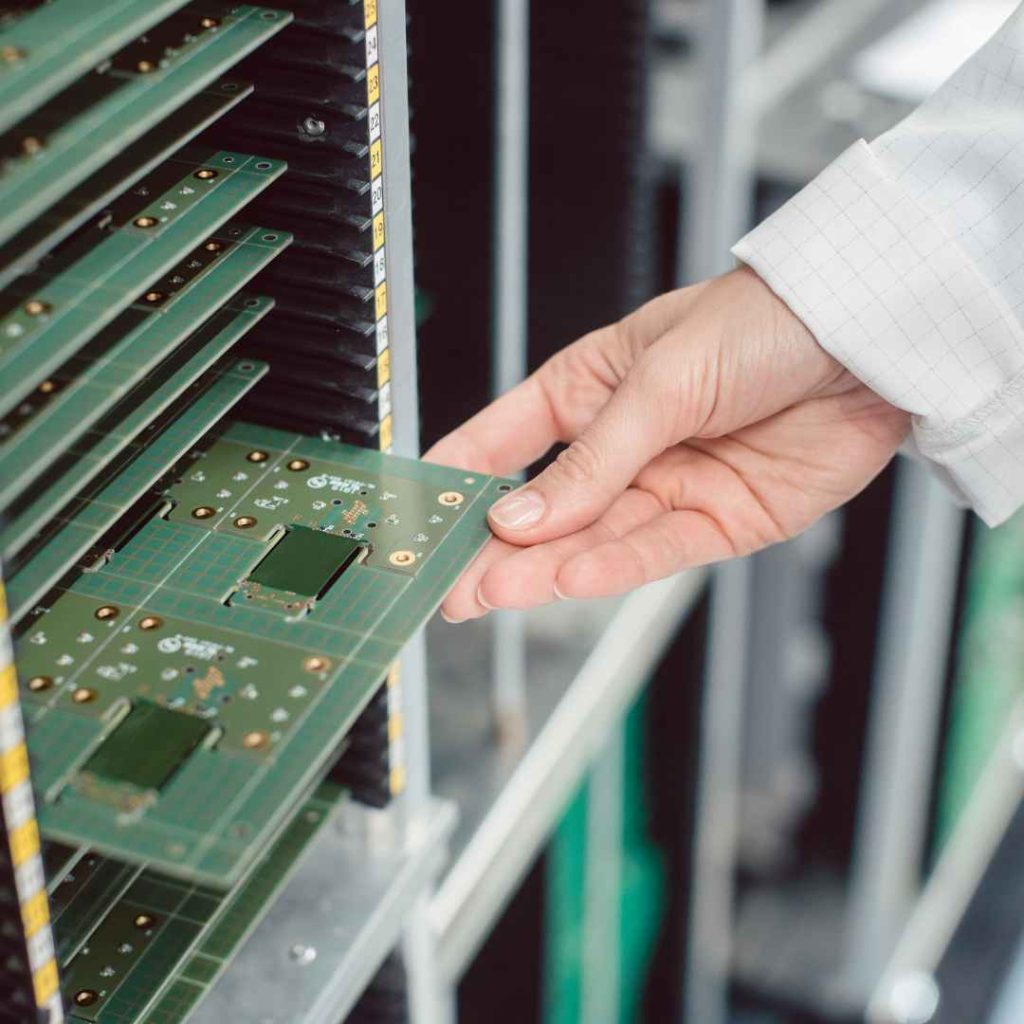 A technician carefully slides a printed circuit board into a densely packed rack, underscoring the critical role of effective PCB layout and construction best practices.